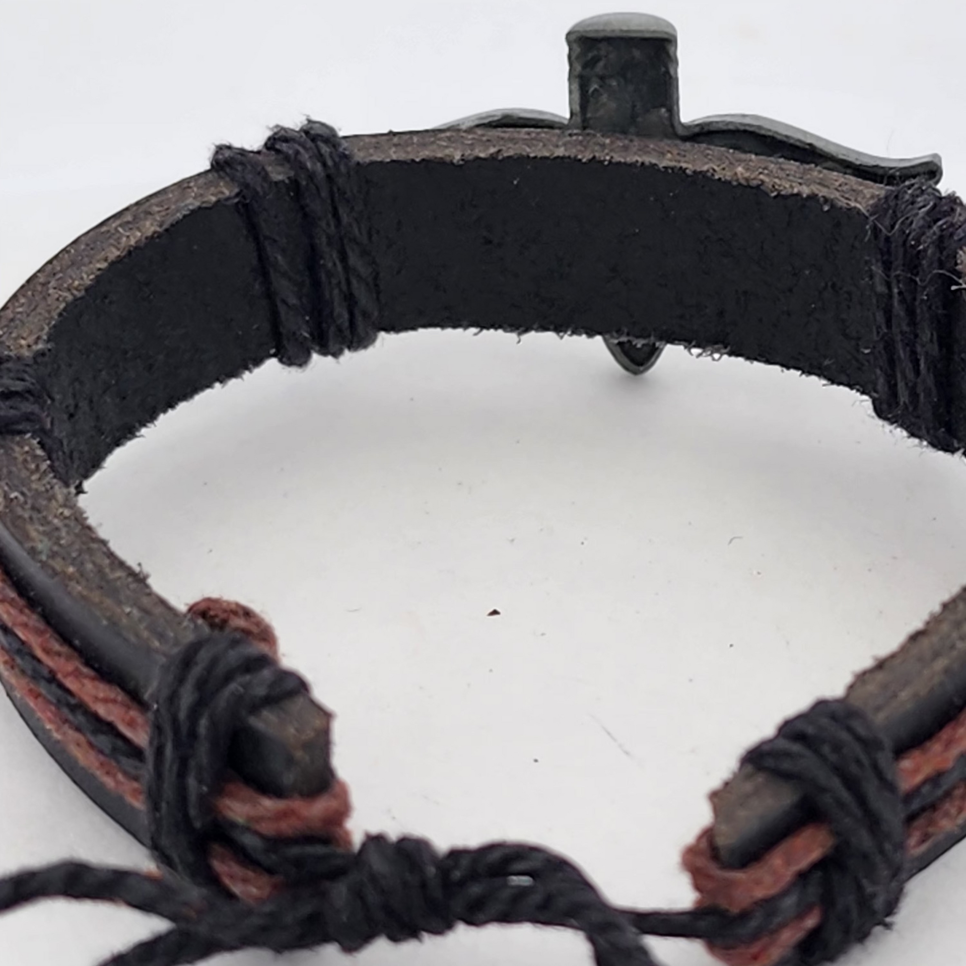 Close-up of a black leather bracelet with braided design on a white background