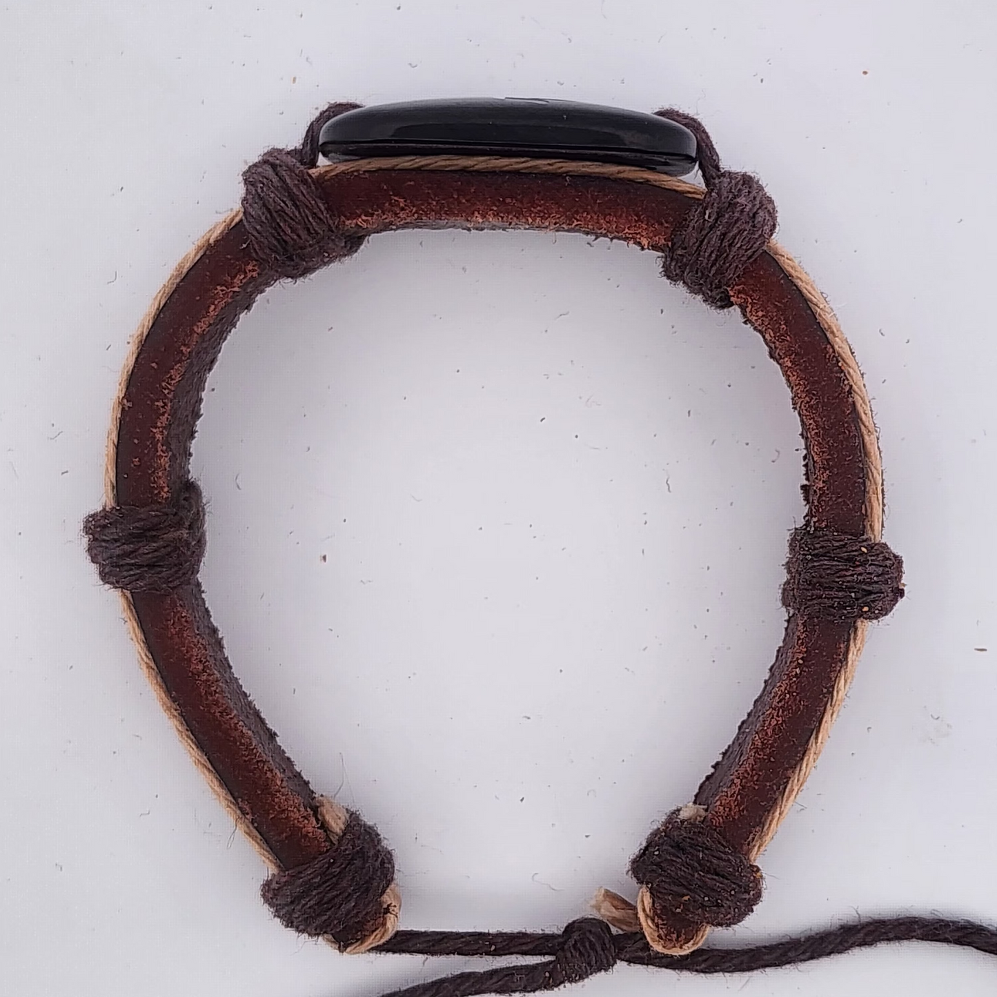 Brown leather bracelet with black cord on a white background