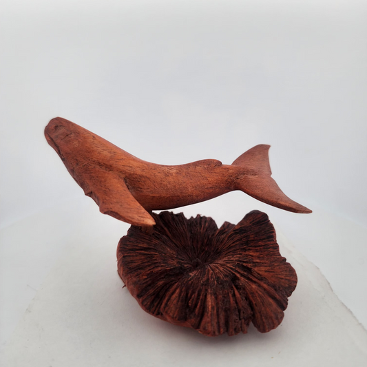 Wooden shark figurine on a textured brown base against a white background