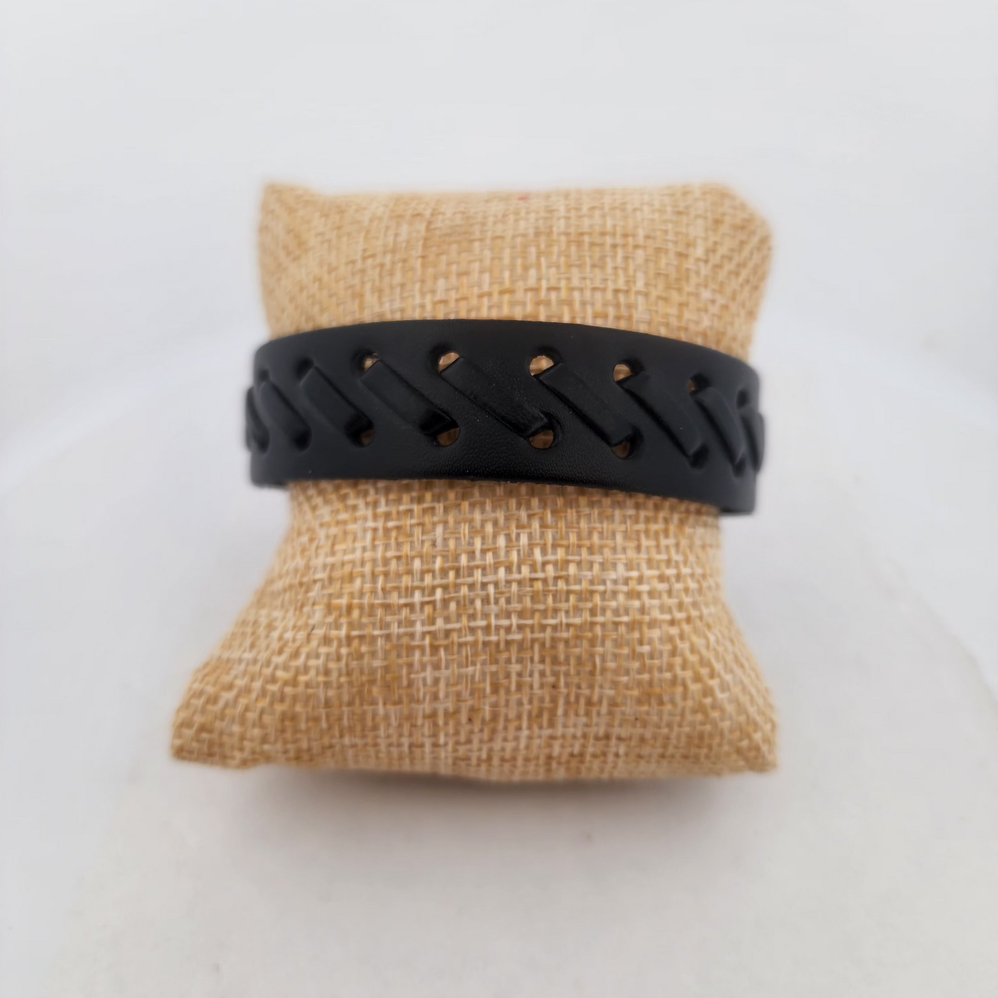Black bracelet on a burlap pillow against a white background