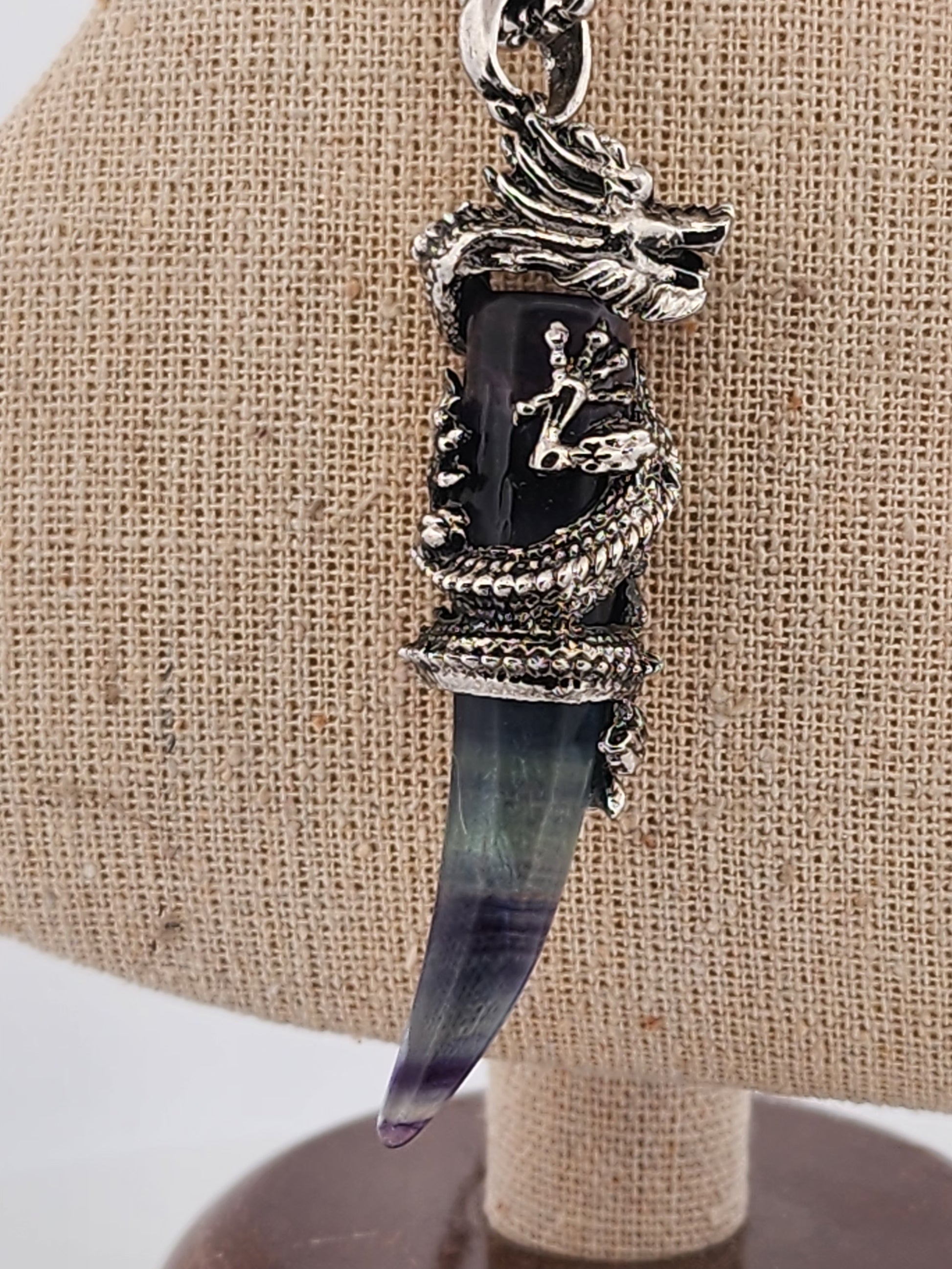 Pendant with a black stone and silver accents on a beige fabric background