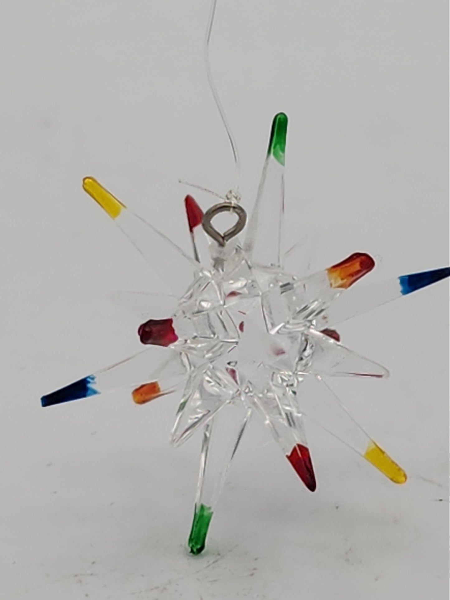 Decorative glass snowflake with colorful tips on a white background