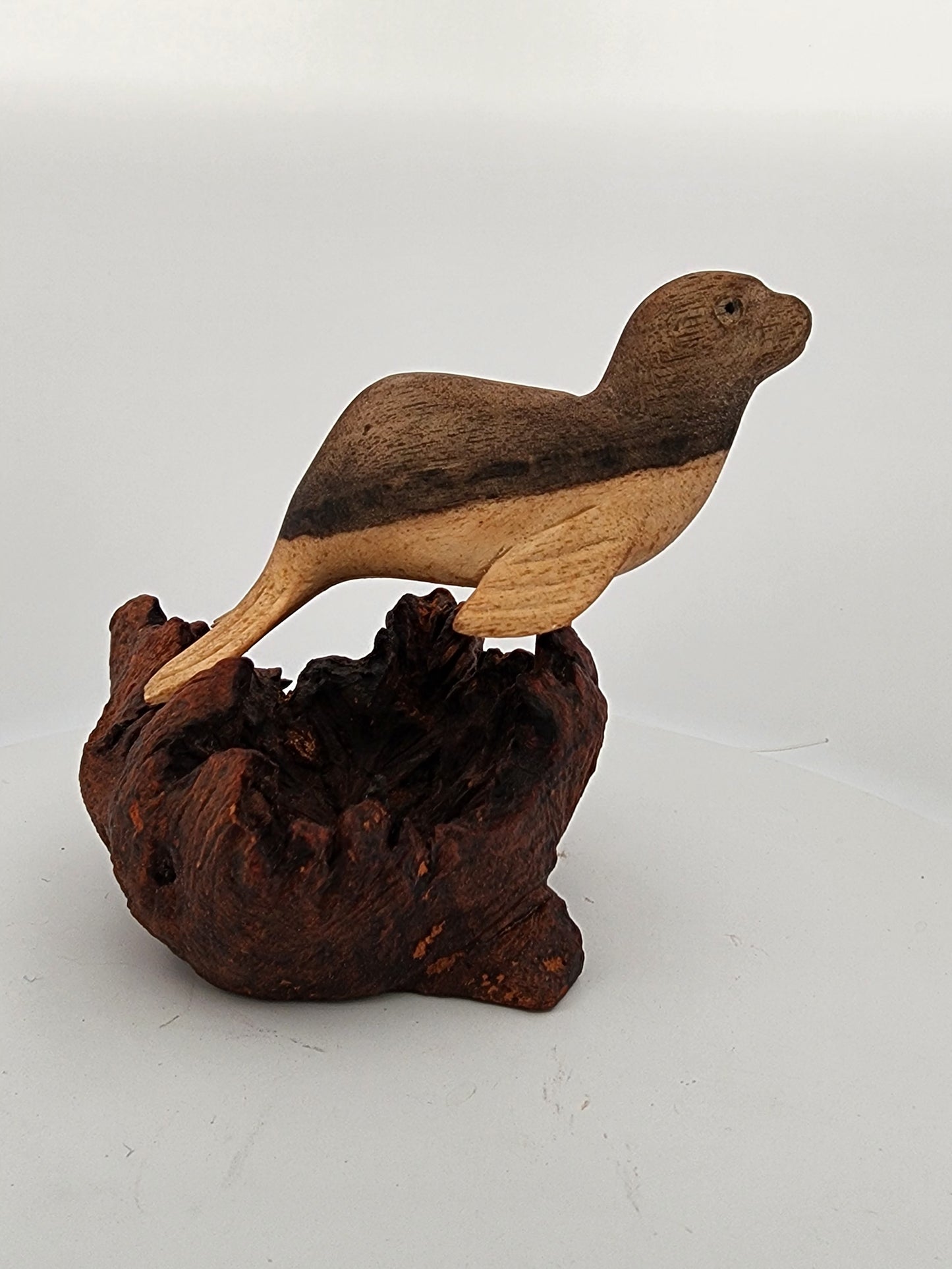 Wooden bird sculpture on a natural wood base against a white background