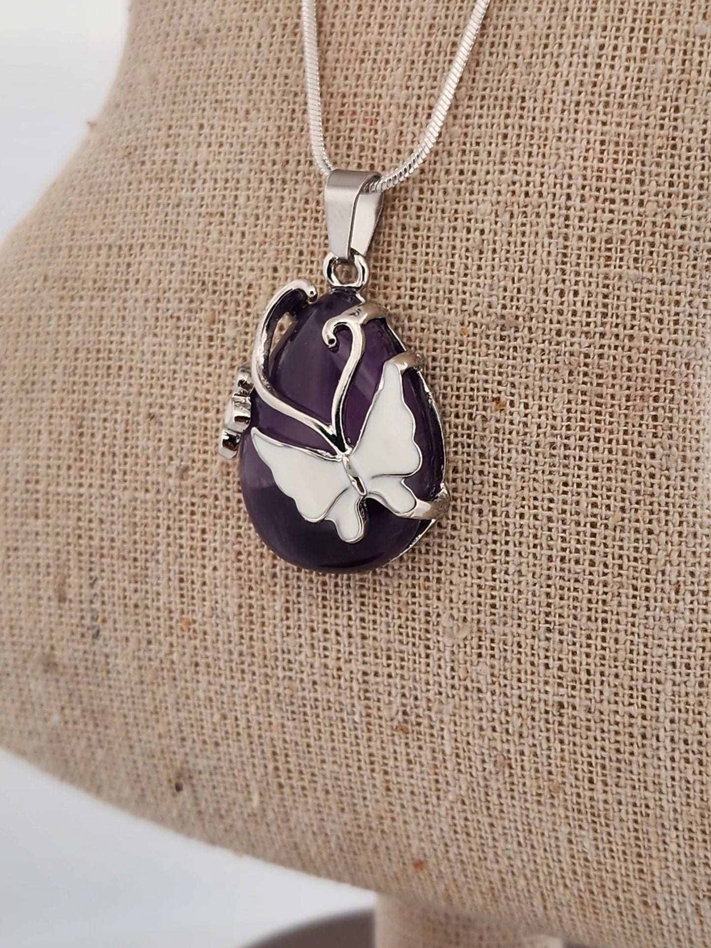 Butterfly pendant necklace on a beige fabric background