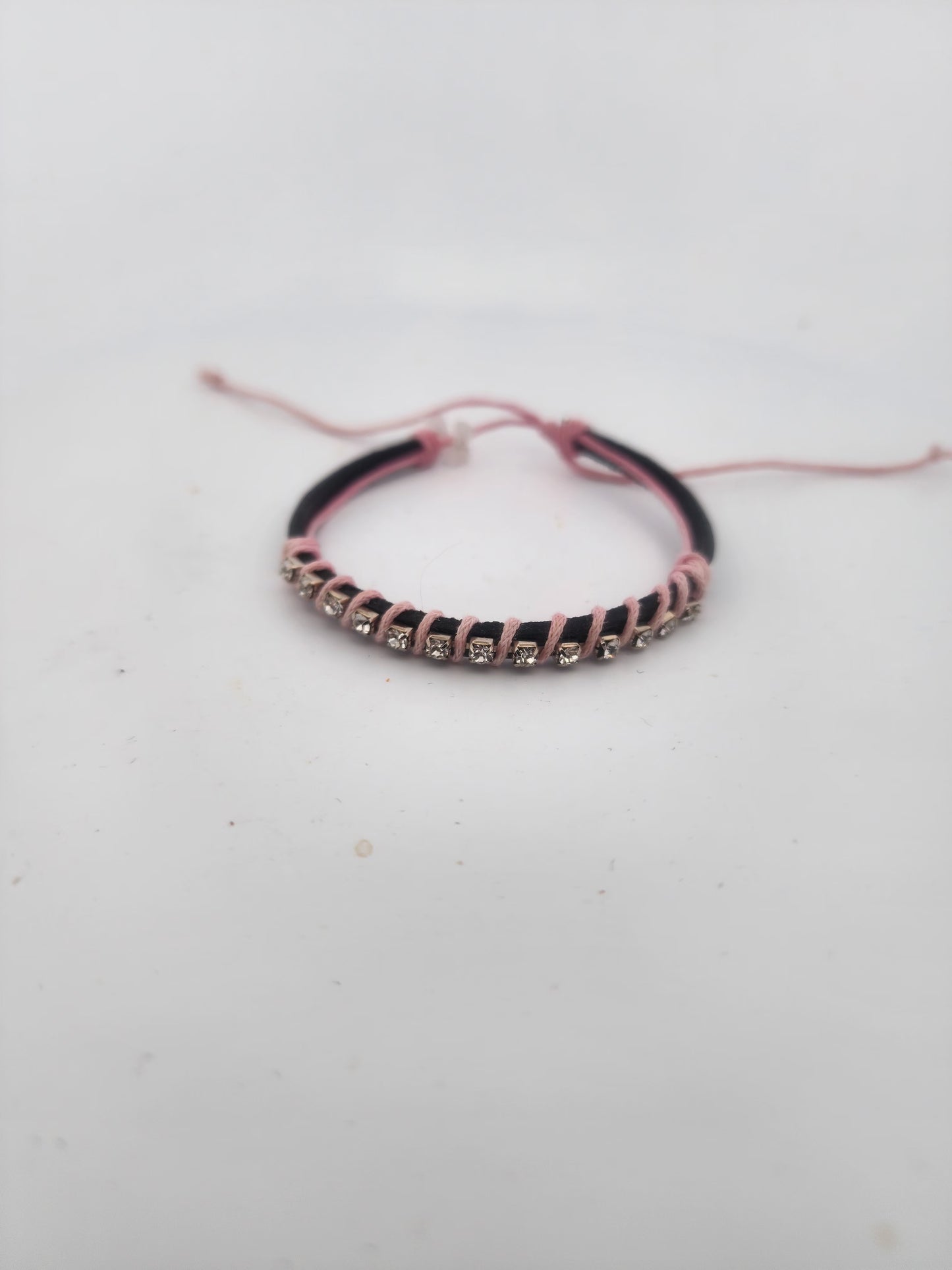 Bracelet with black and pink cord on a light gray background