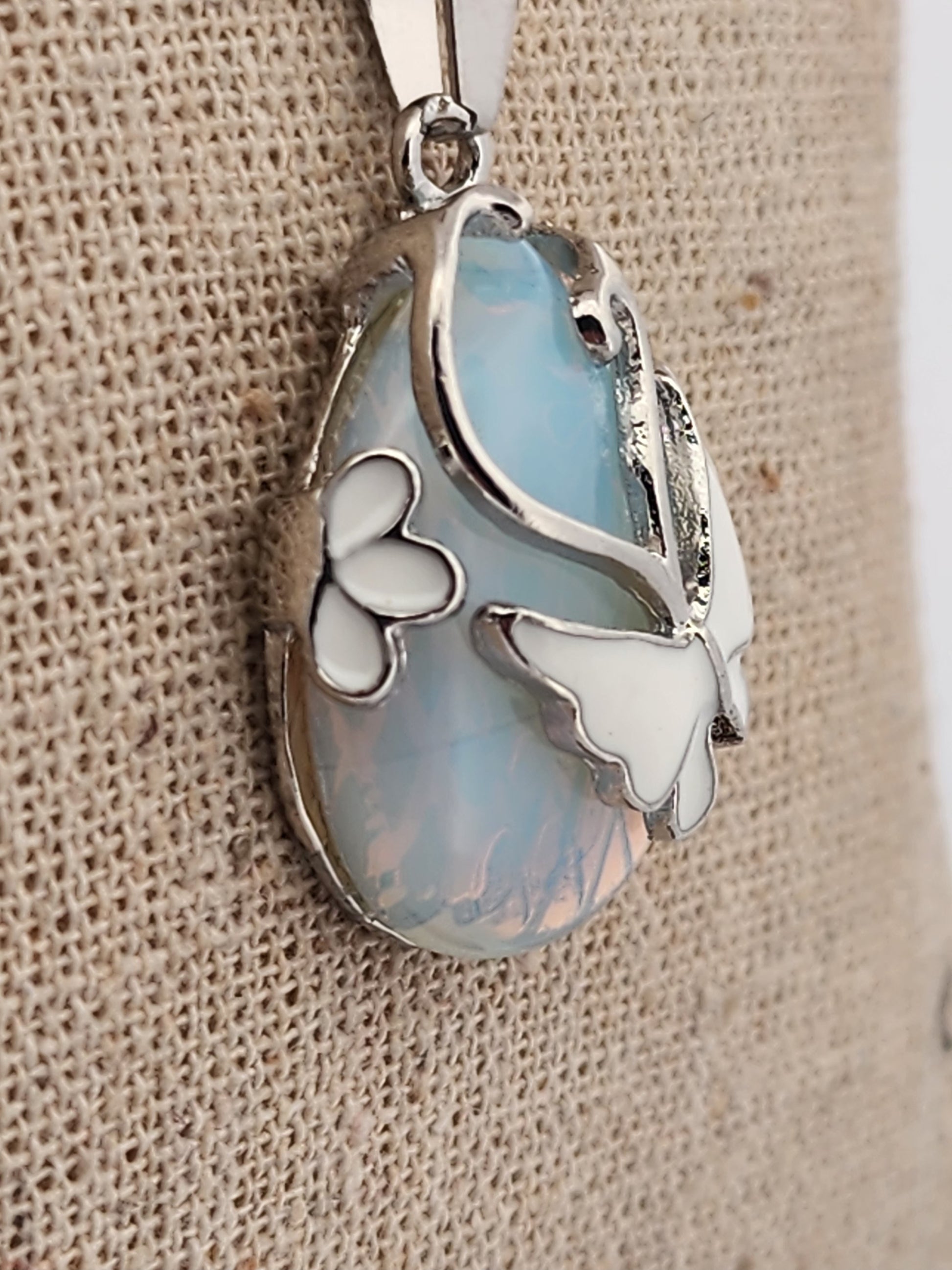 Silver pendant with a light blue stone on a textured beige background
