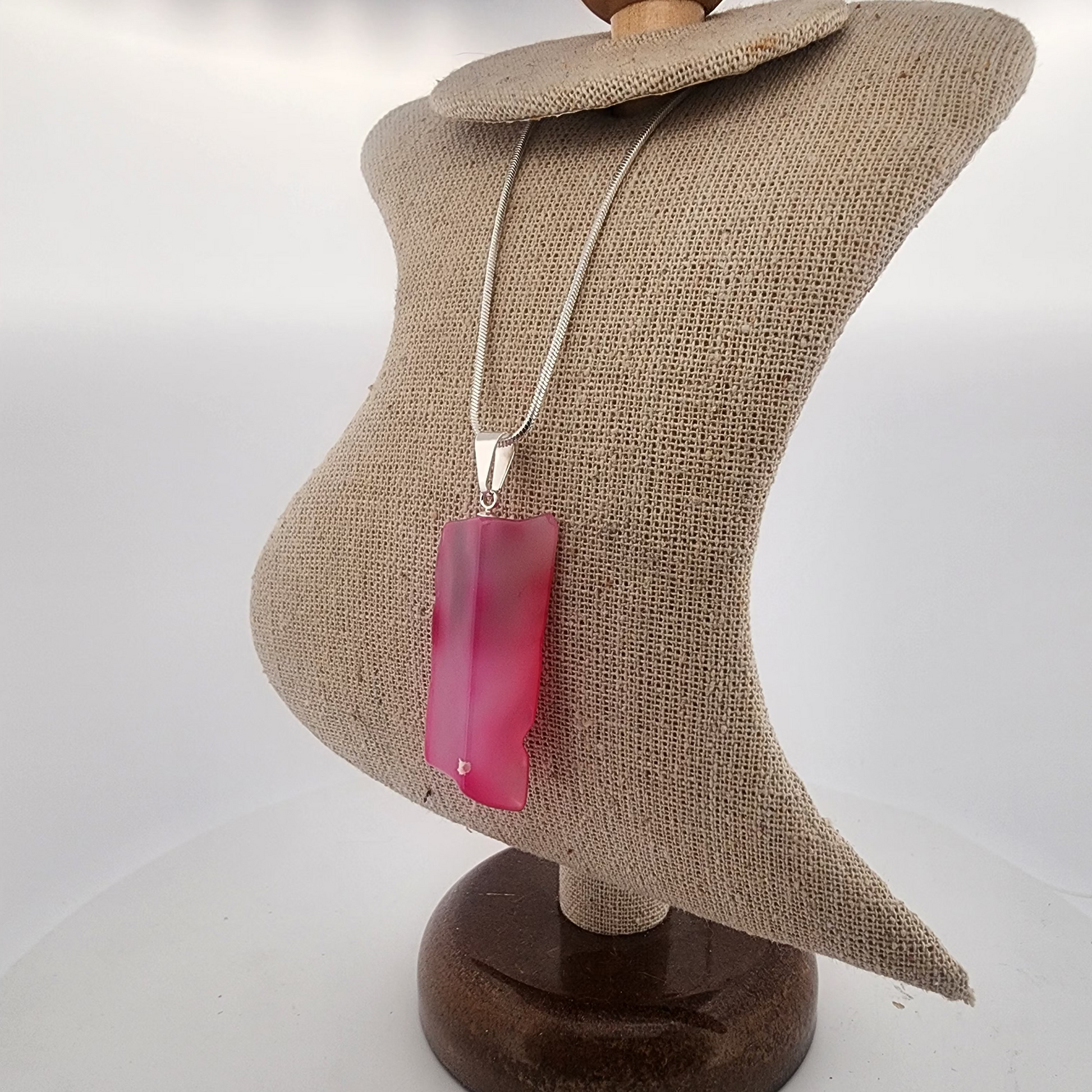 Necklace with a pink pendant on a mannequin bust against a white background
