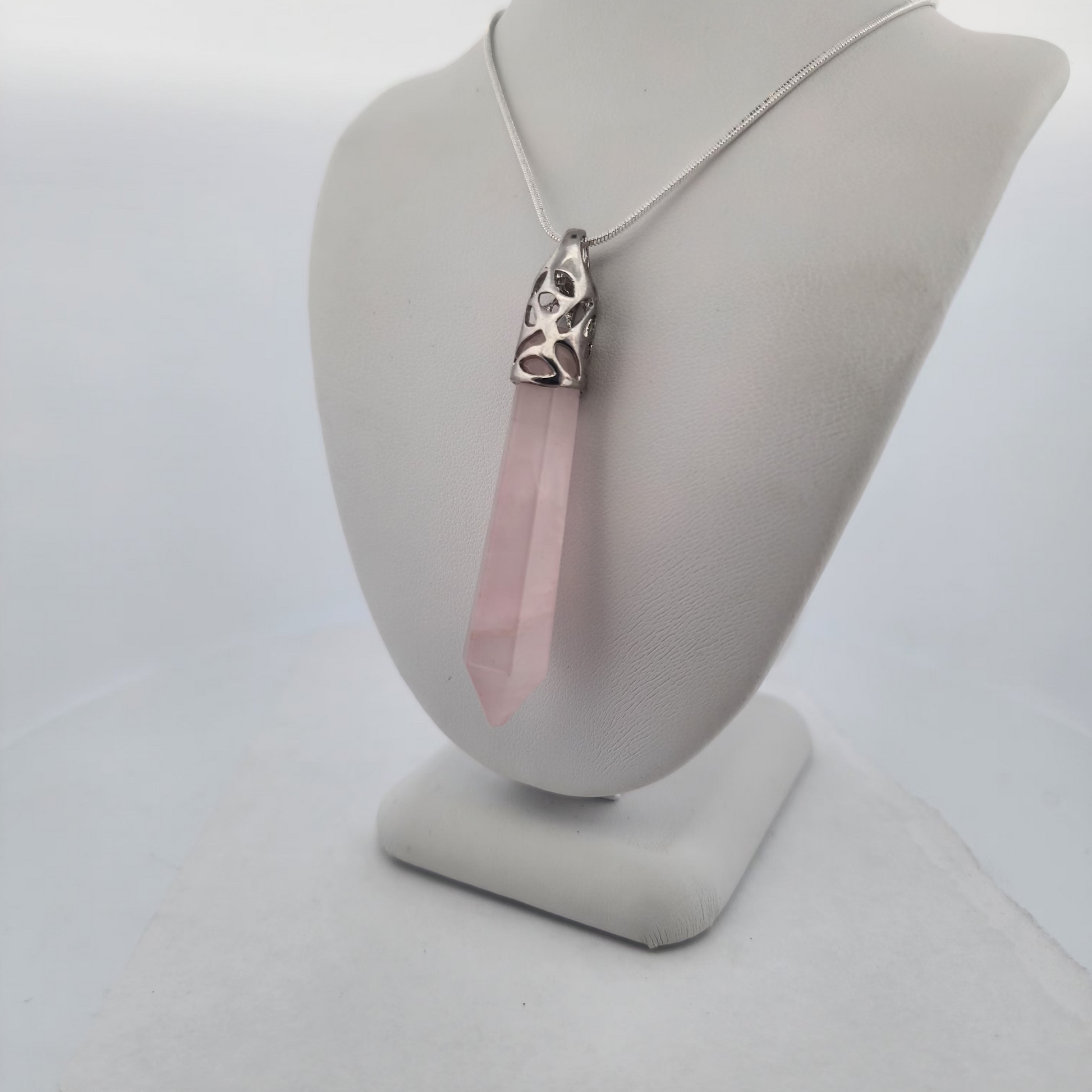 Necklace with a pink crystal pendant on a gray mannequin bust against a white background