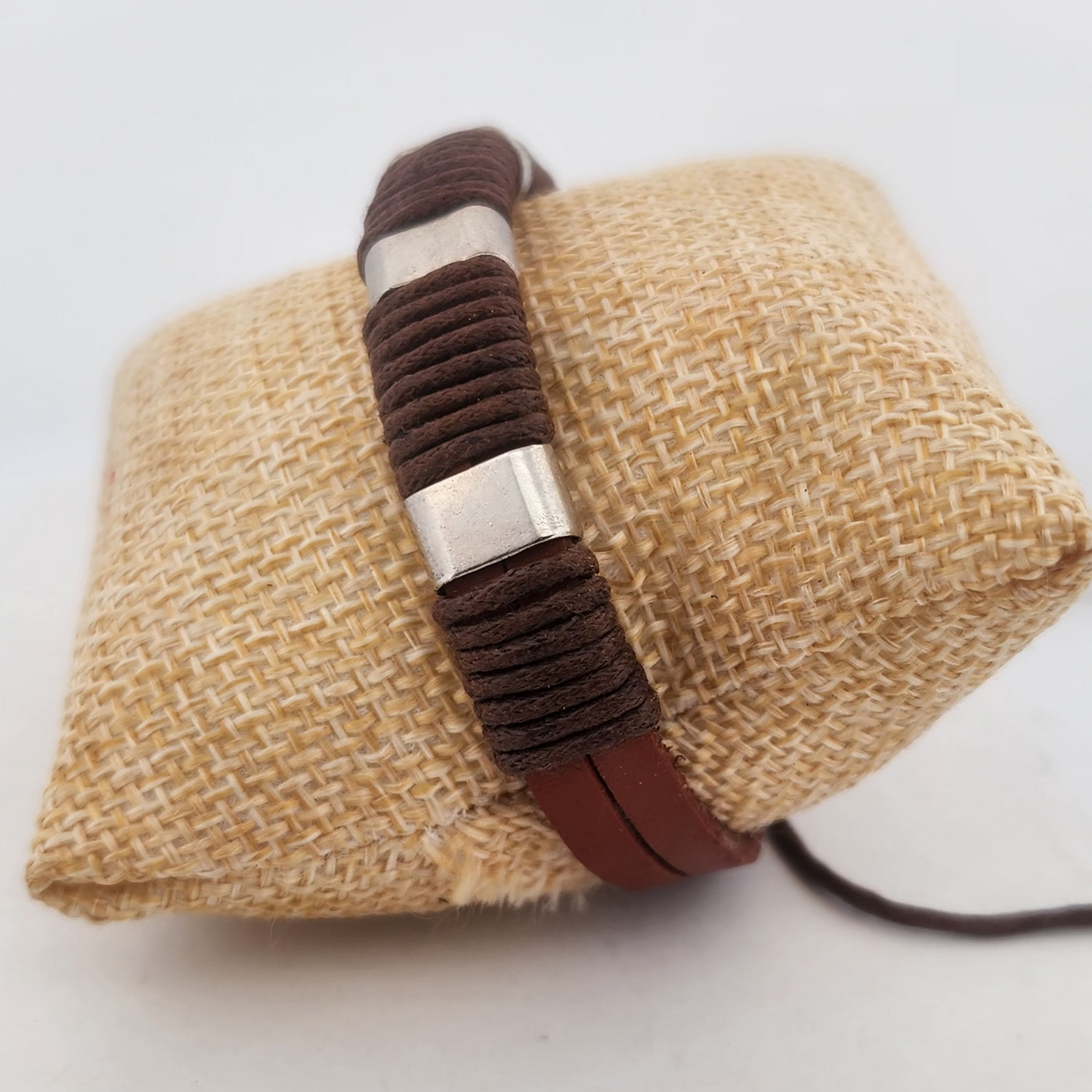 Bracelet with brown woven design on a textured beige surface