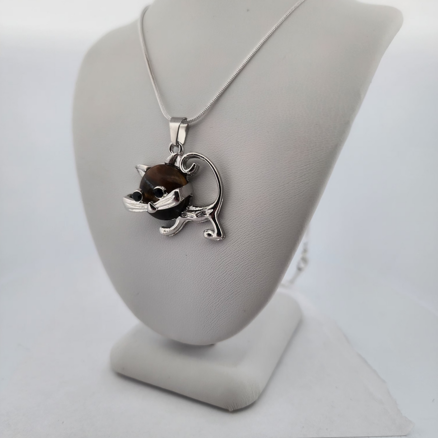 Silver necklace with a cat pendant on a white stand against a white background