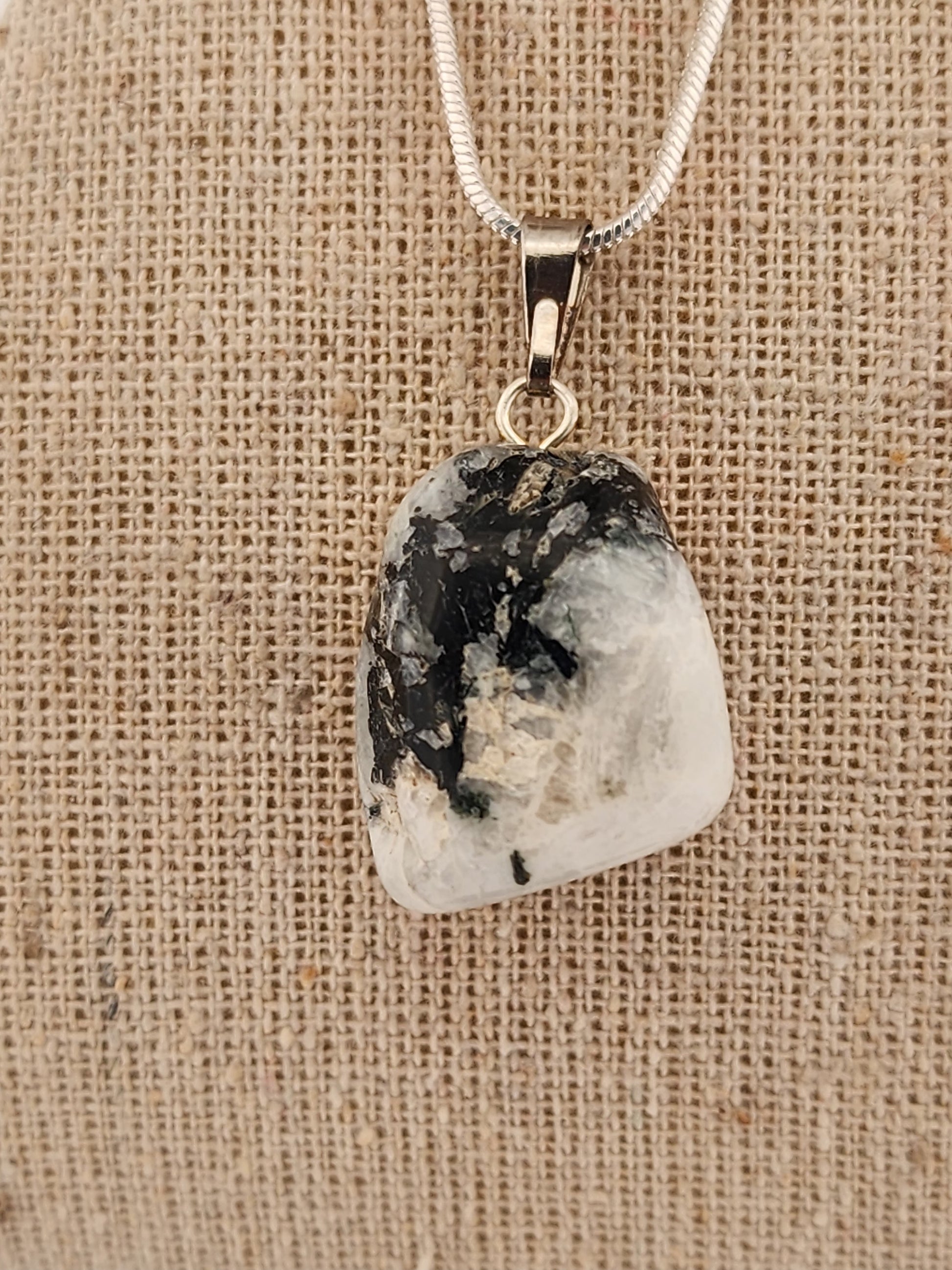 Necklace with a pendant featuring a natural stone on a textured beige background