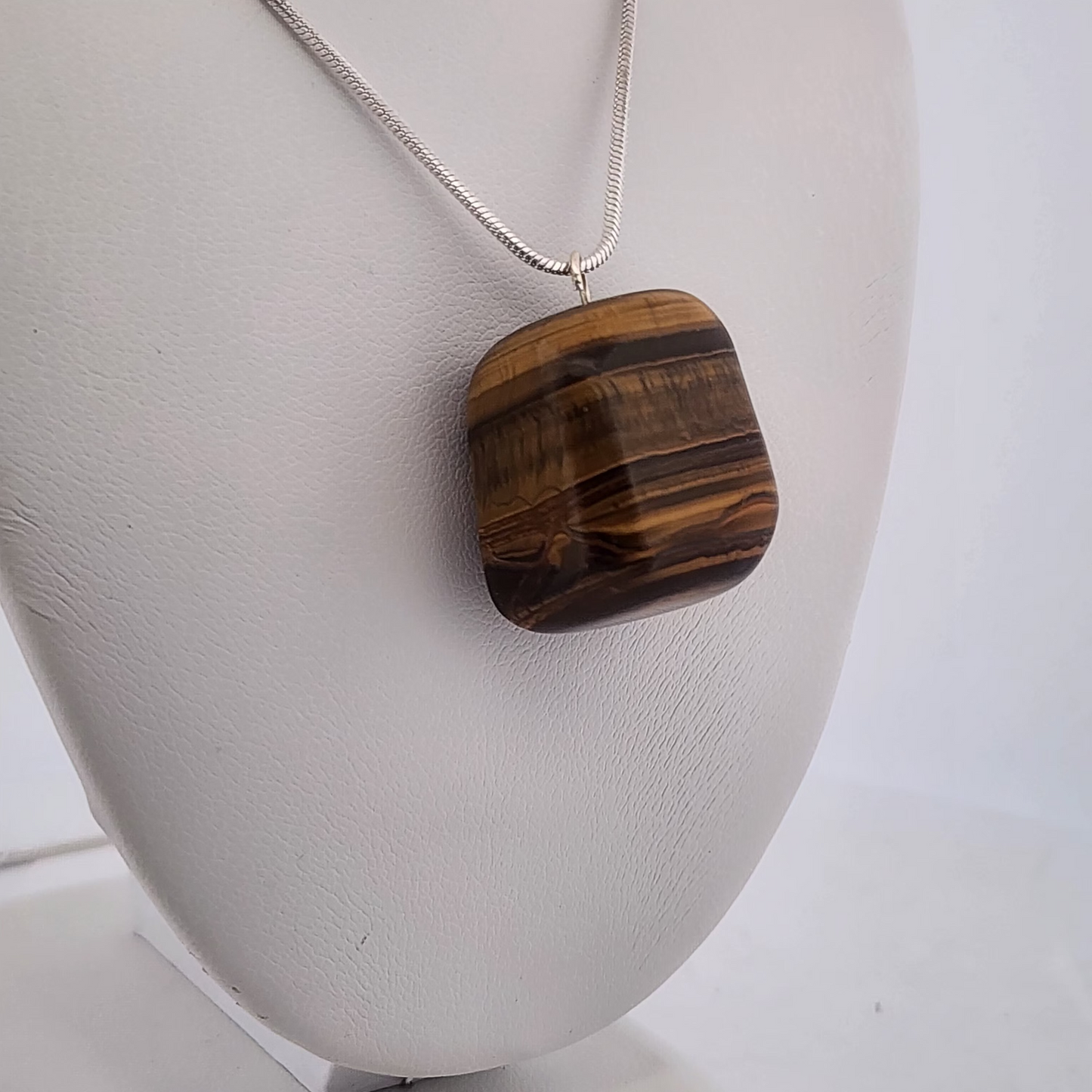 Necklace with a Tiger eye pendant on a white stand