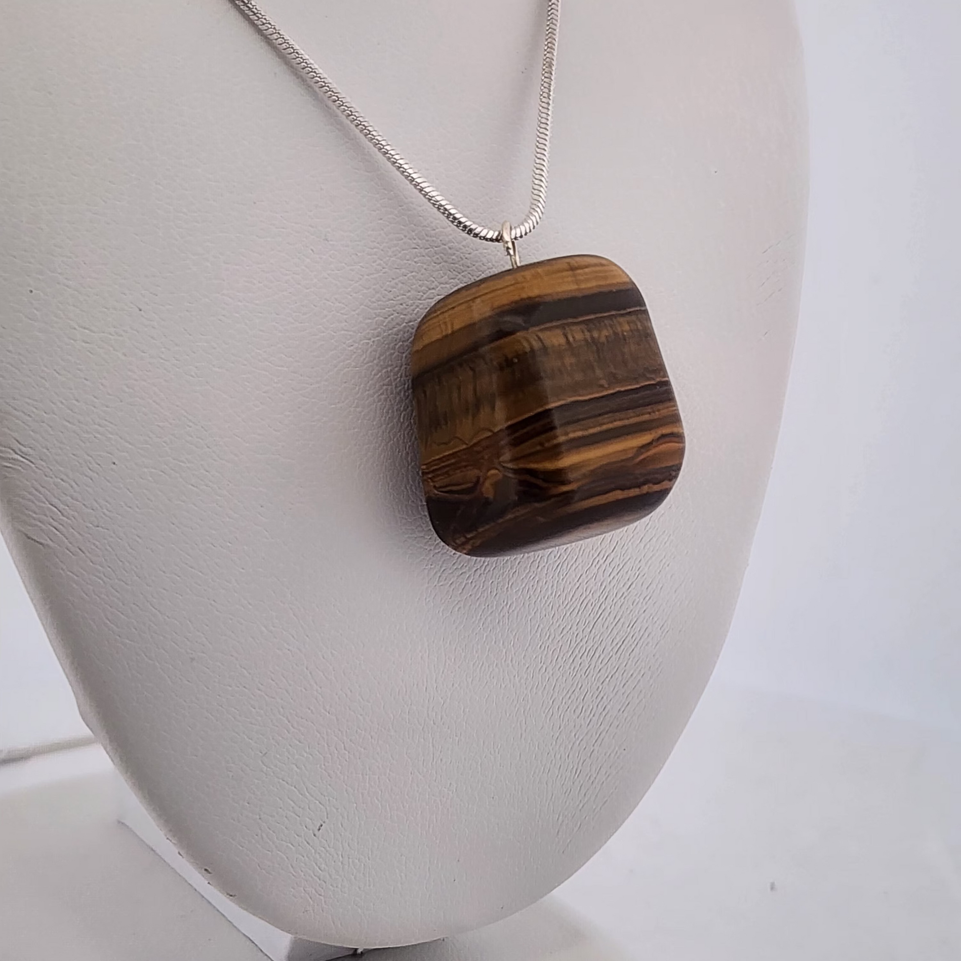 Necklace with a Tiger eye pendant on a white stand