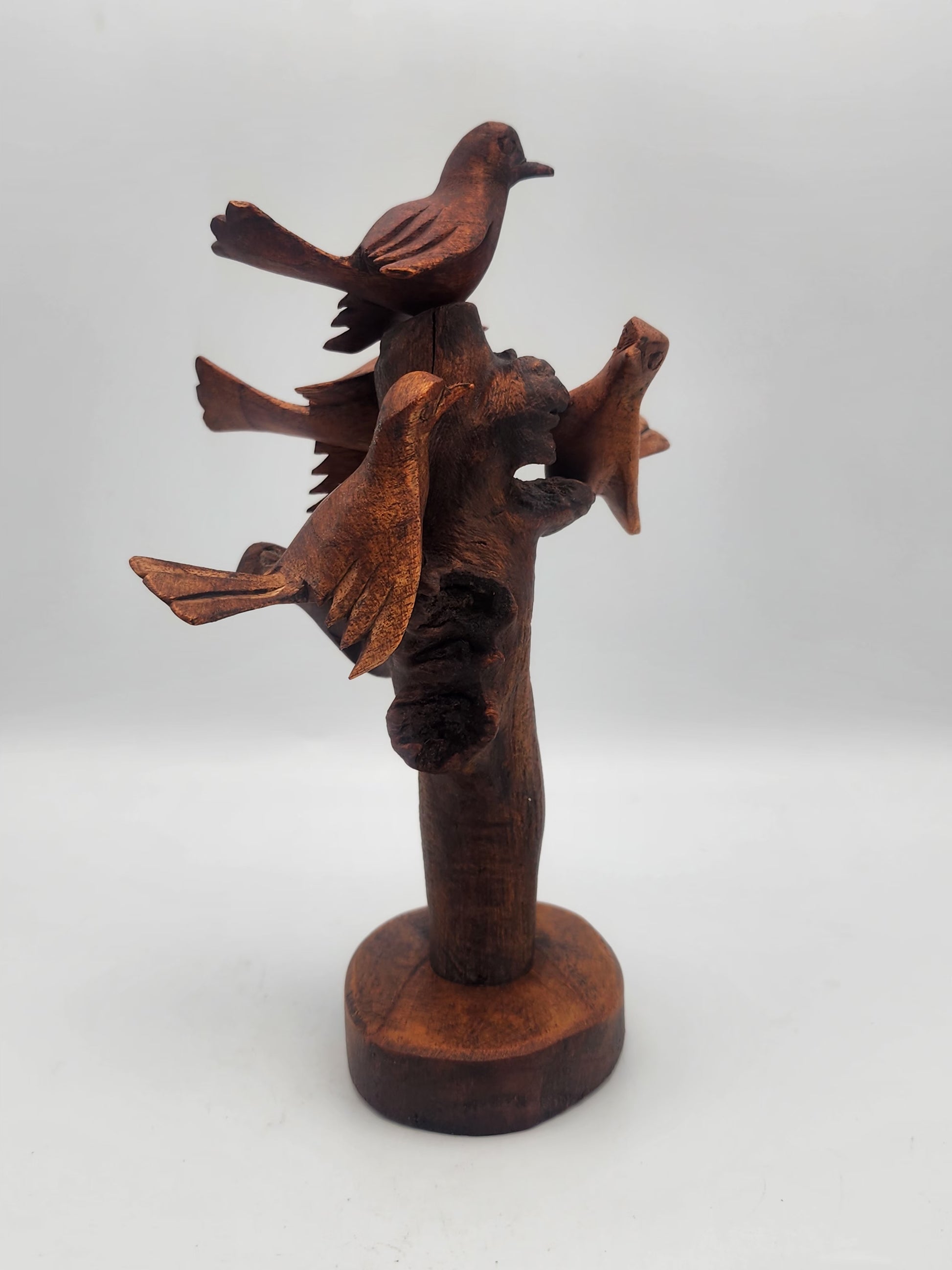 Wooden sculpture of birds perched on a branch on a white background
