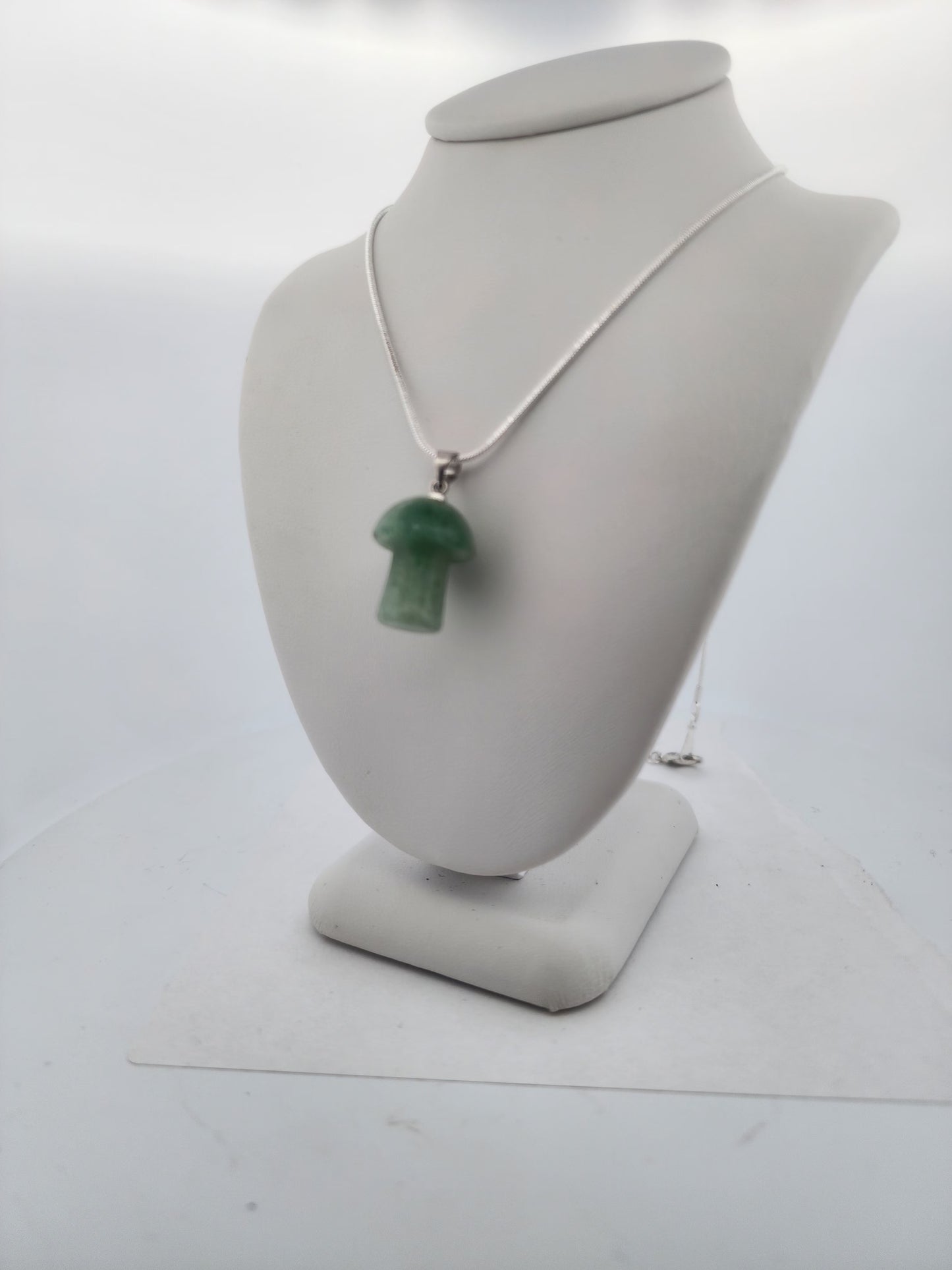 Necklace with a green pendant on a mannequin bust against a white background
