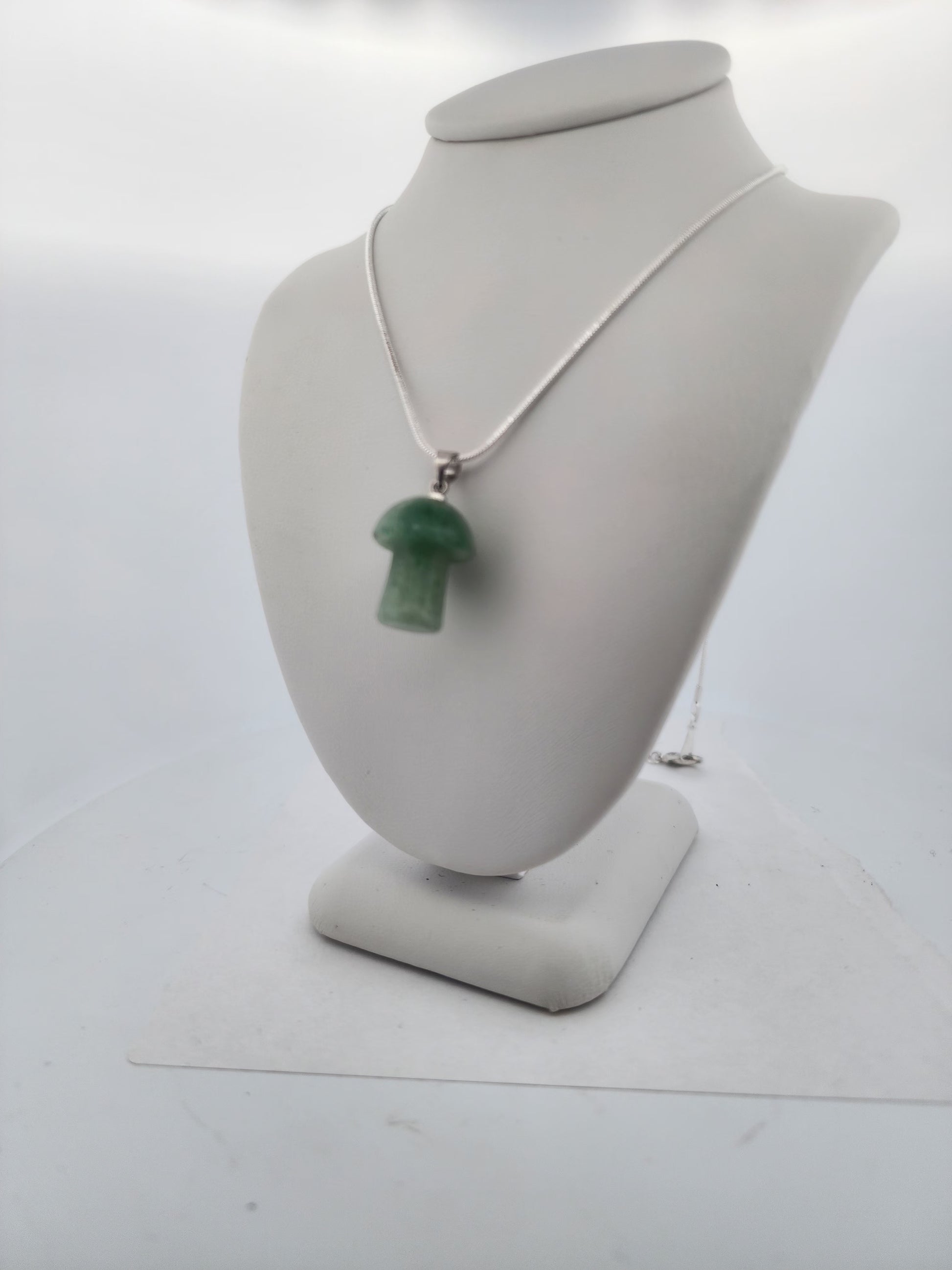 Necklace with a green pendant on a mannequin bust against a white background