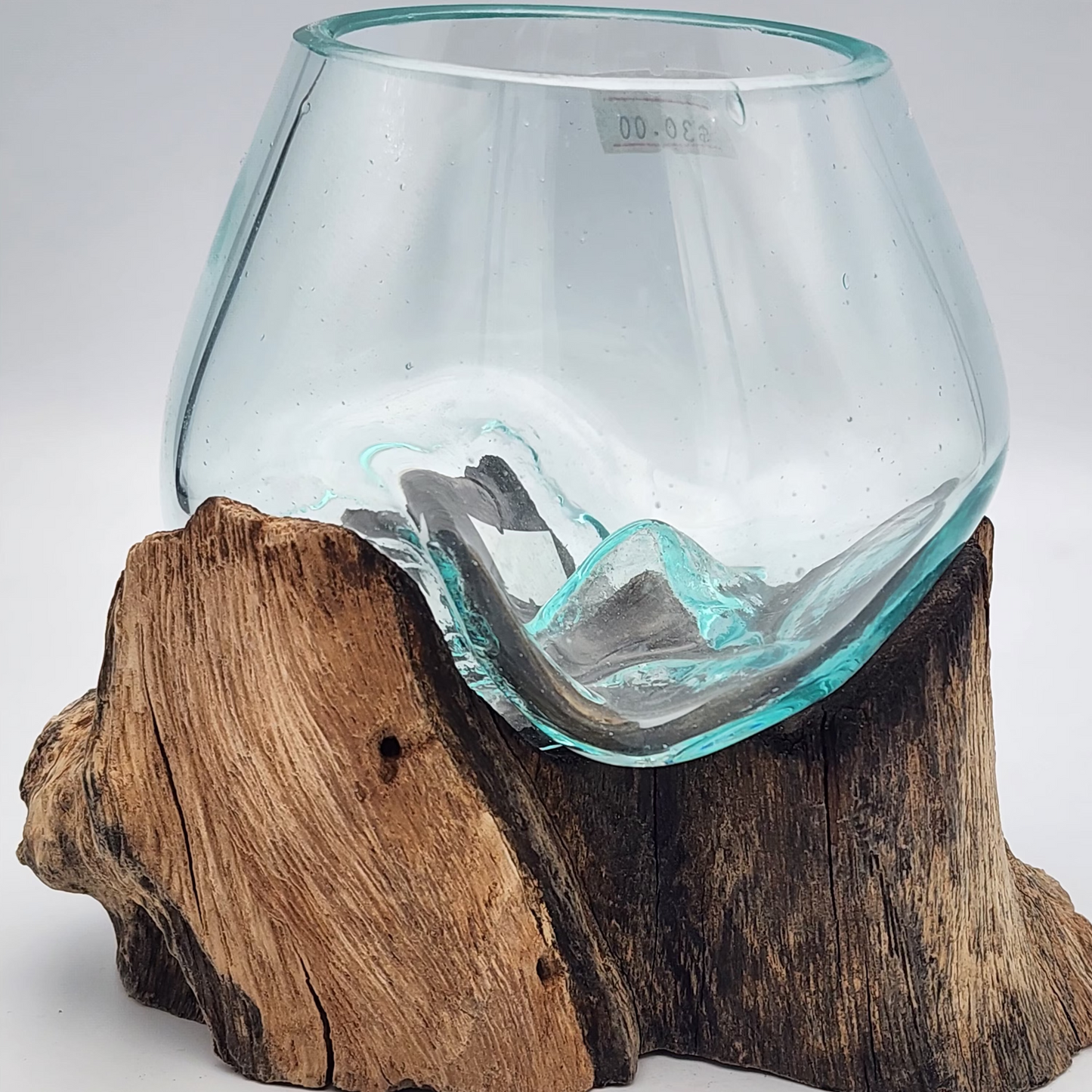 Clear glass vase on a wooden base against a gray background