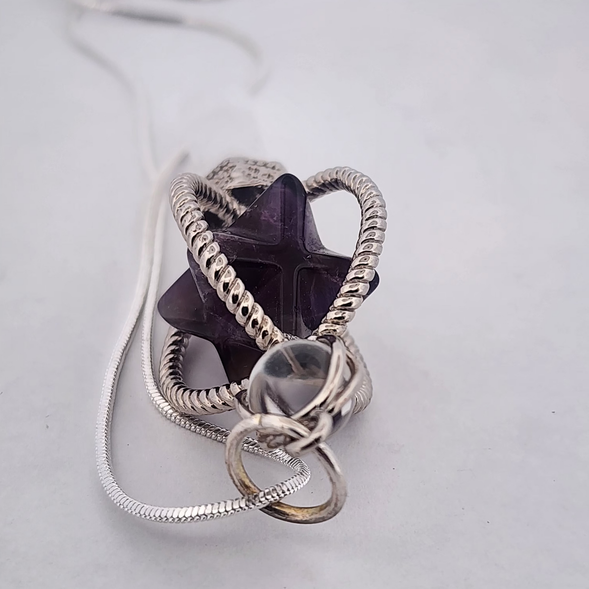 Silver necklace with a star-shaped pendant on a light gray background