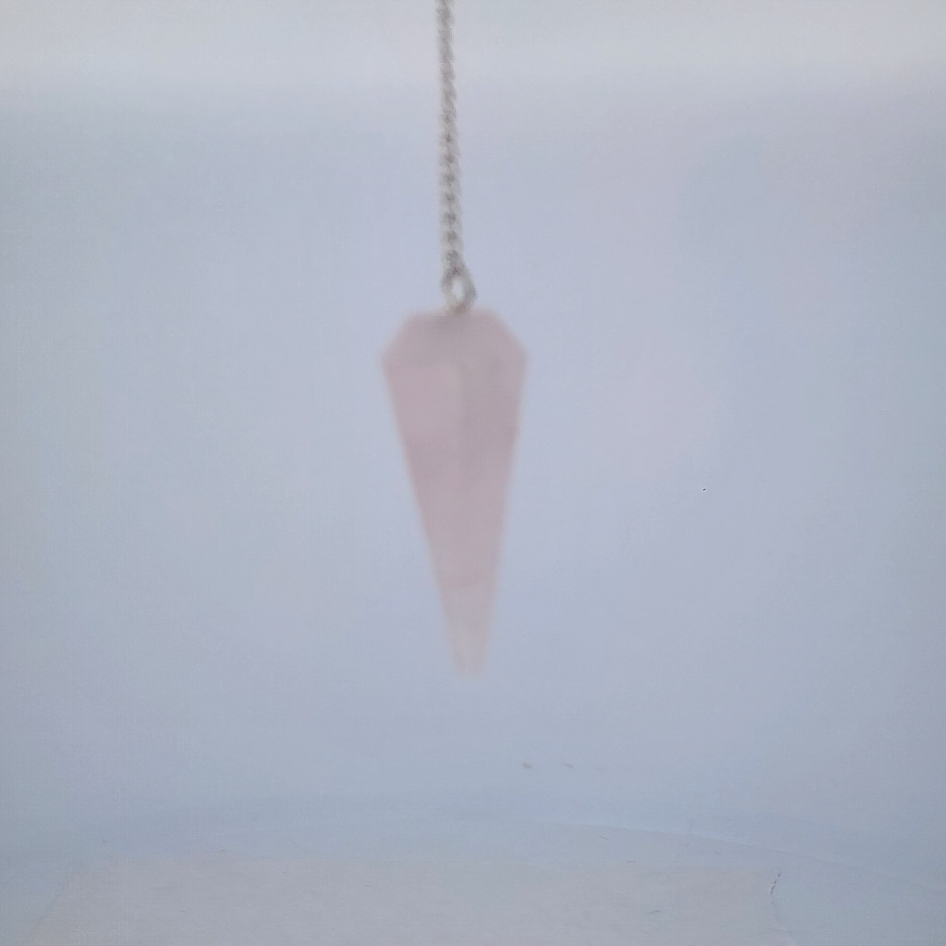 Pink crystal pendulum on a light gray background