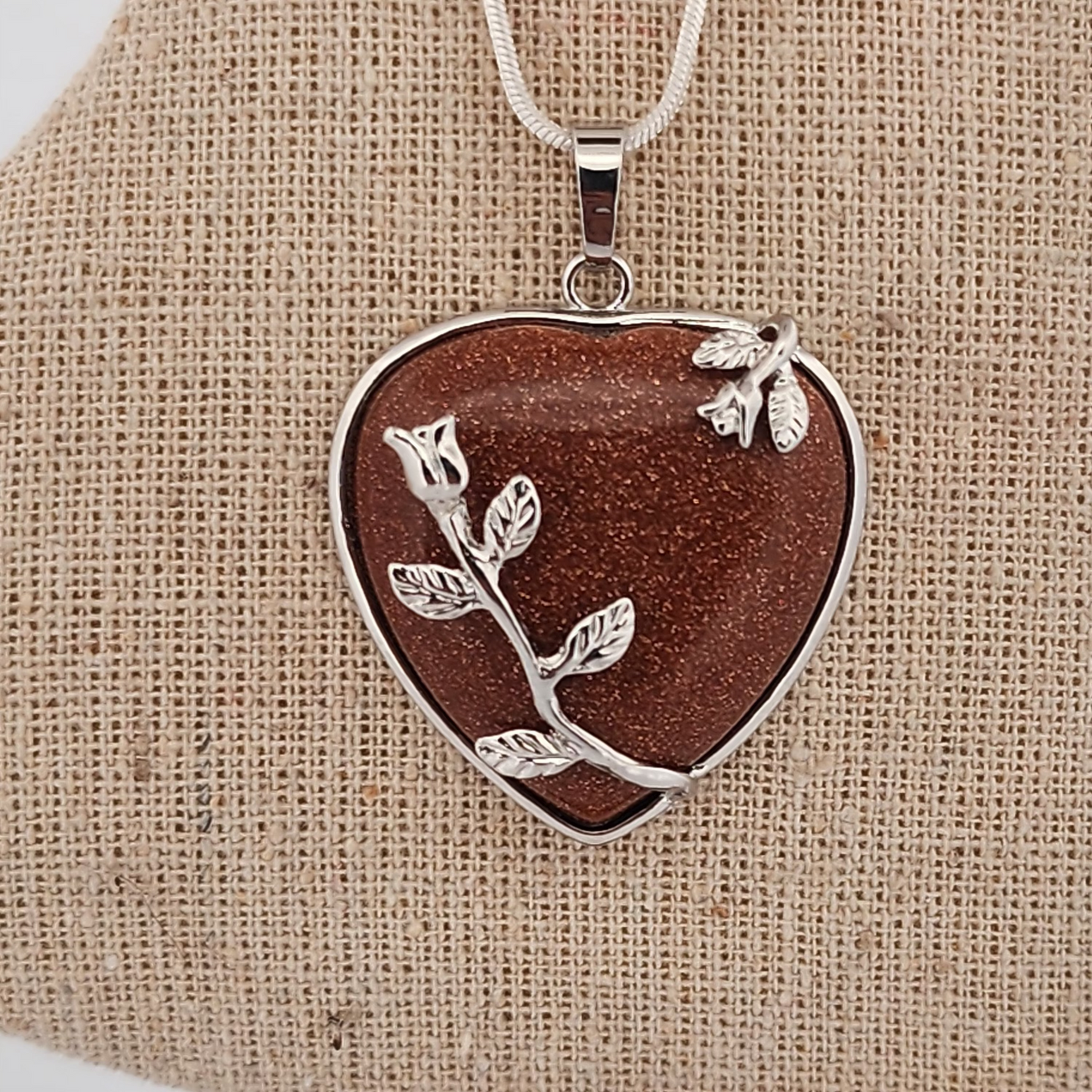 Heart-shaped pendant with floral design on a beige stand