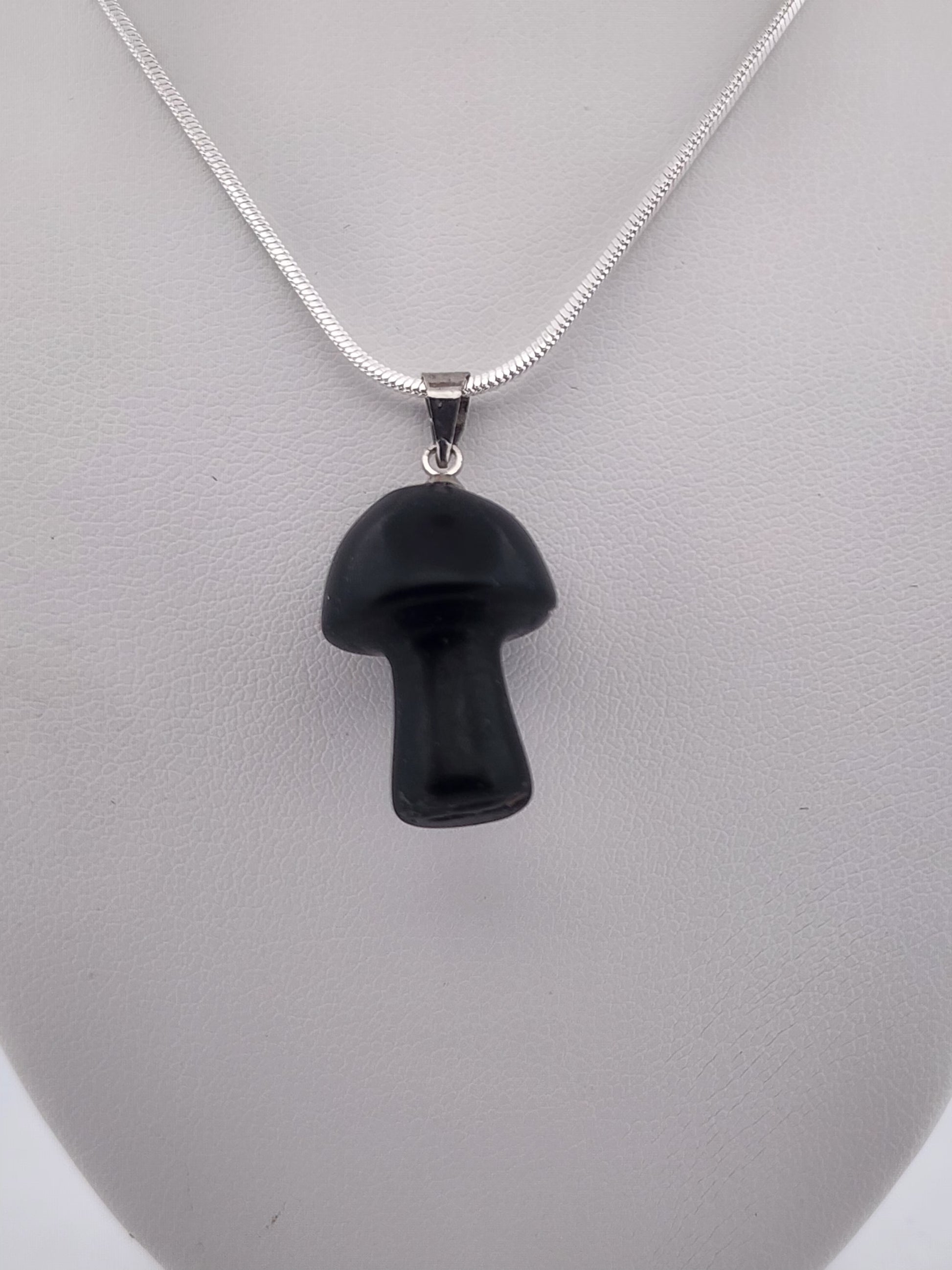 Black mushroom-shaped pendant on a silver chain against a gray background