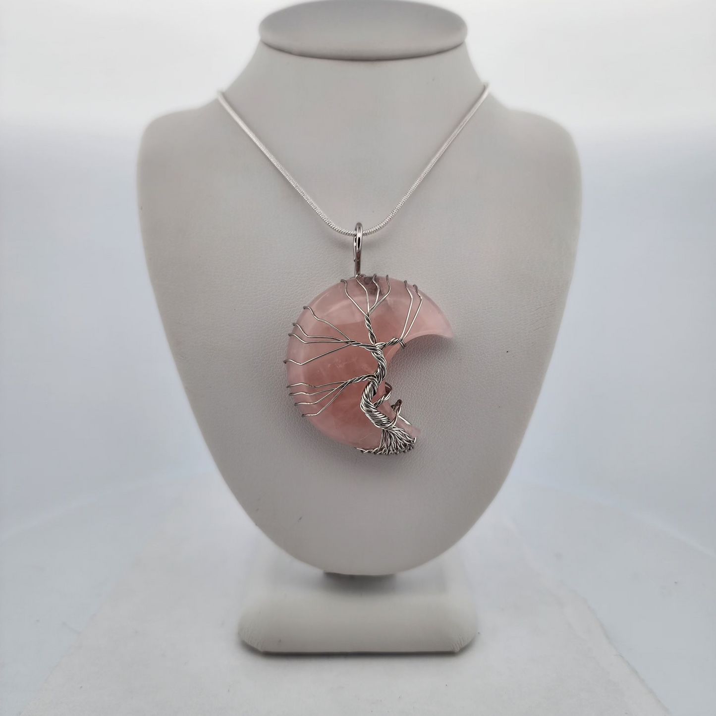 Necklace with a pink pendant on a white mannequin bust against a white background