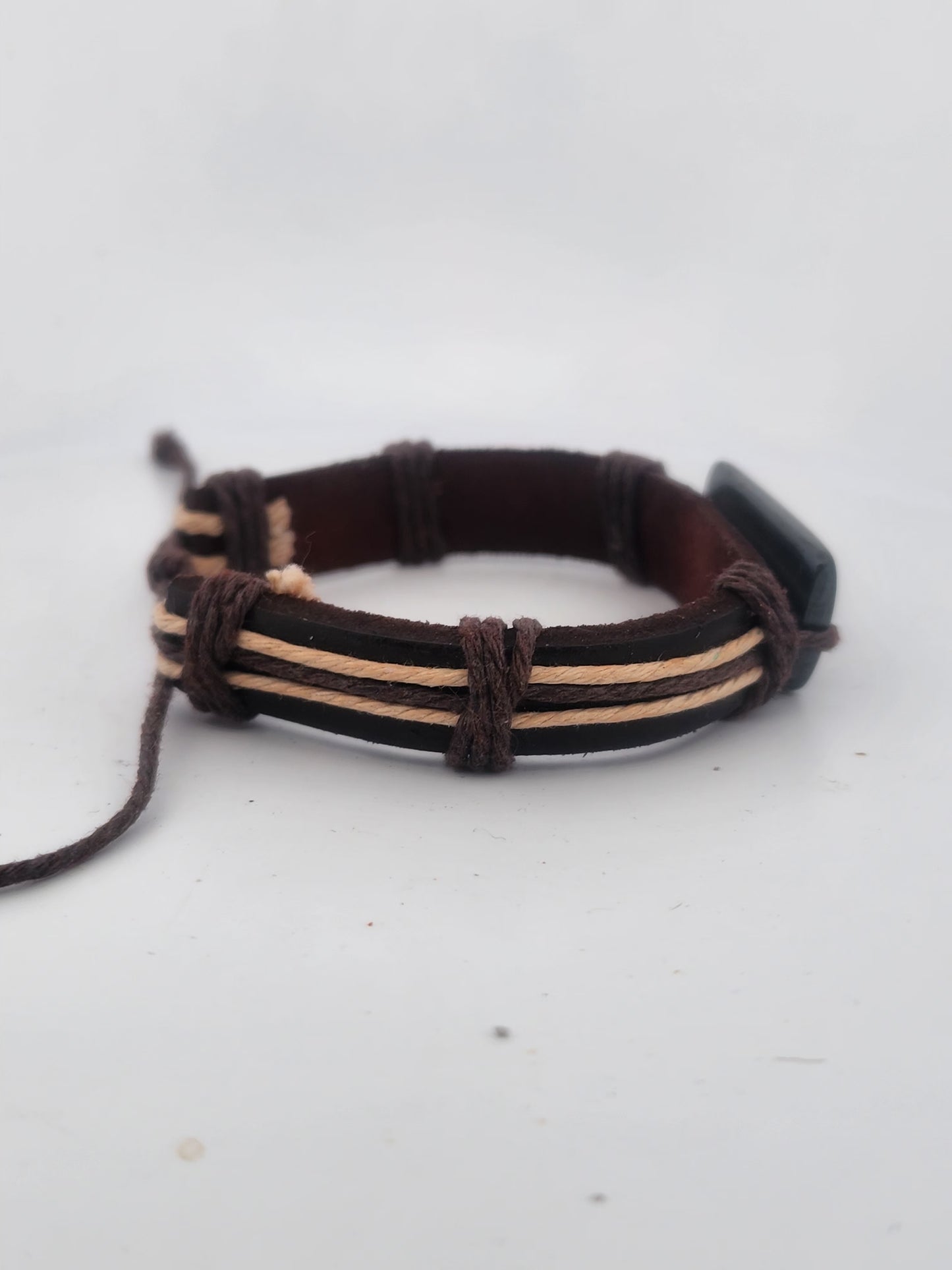 Brown leather bracelet with beige accents on a light gray background
