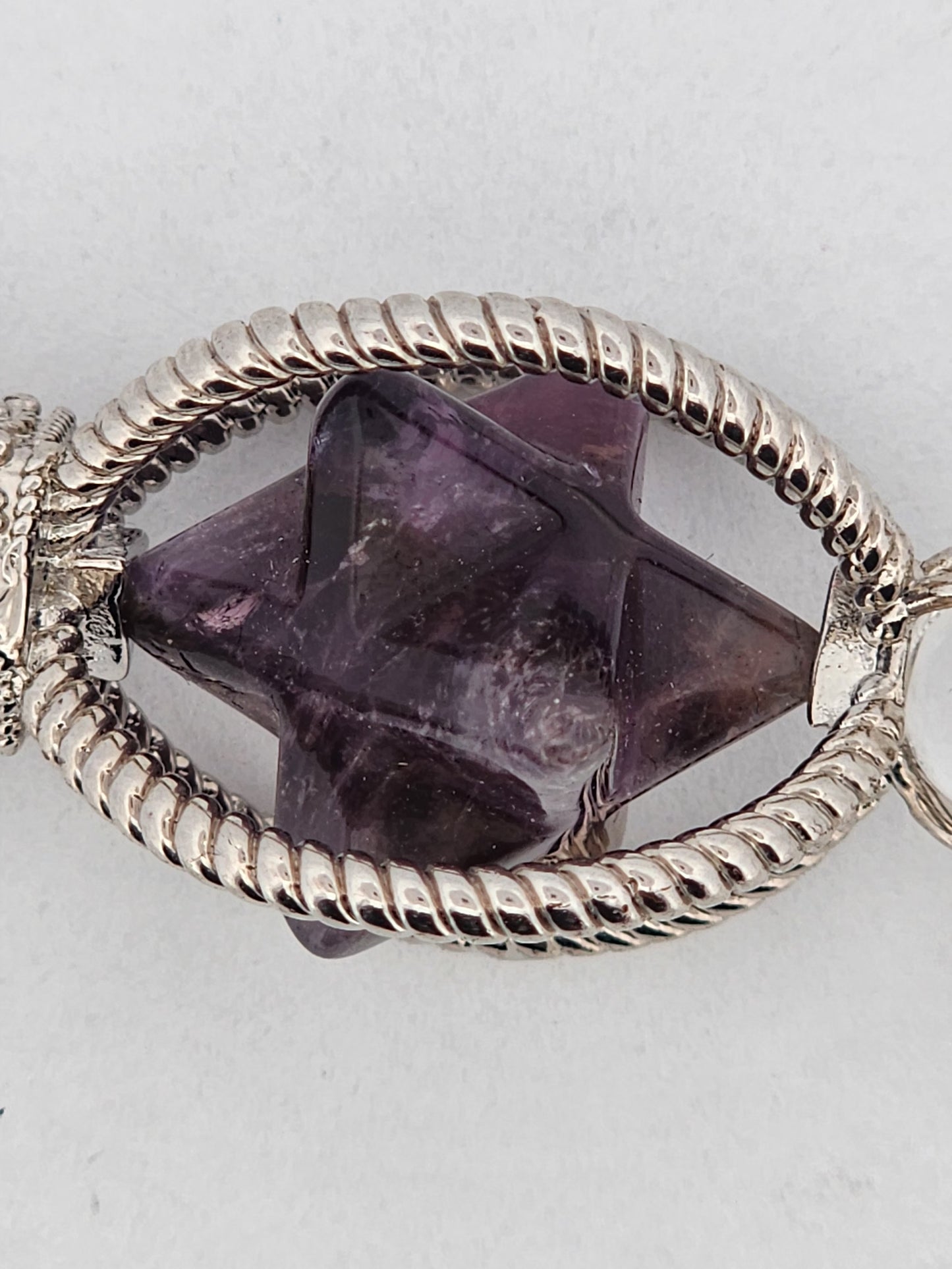Purple crystal in a silver frame on a light gray background