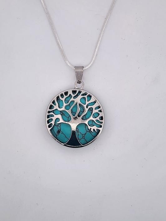 Silver necklace with a turquoise tree of life pendant on a light gray background