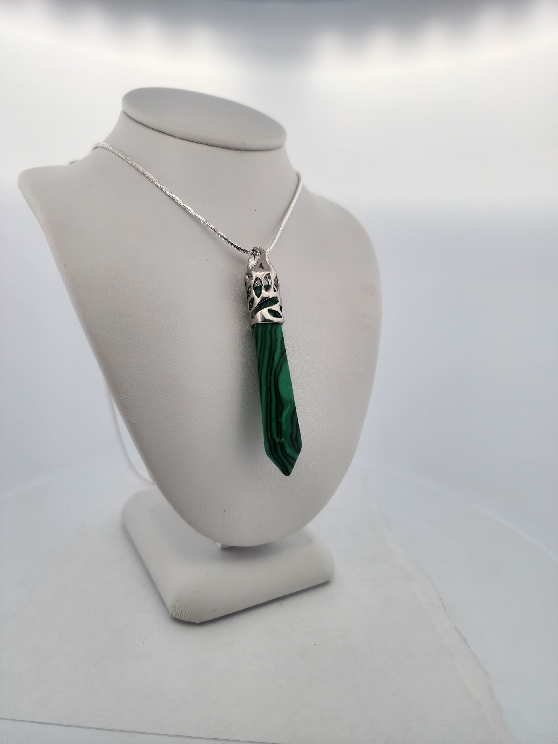 Necklace with a green pendant on a mannequin bust against a white background