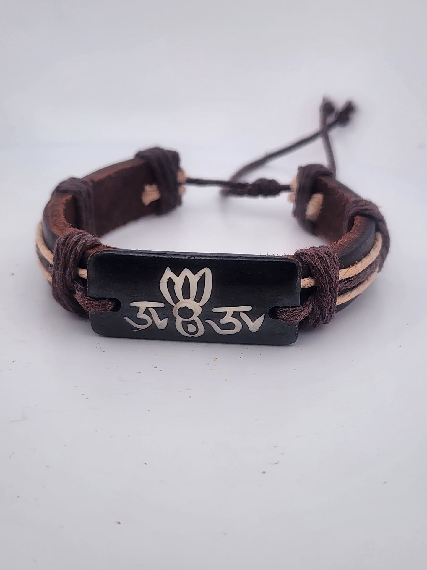 Bracelet with brown leather strap and black metal tag on a white background