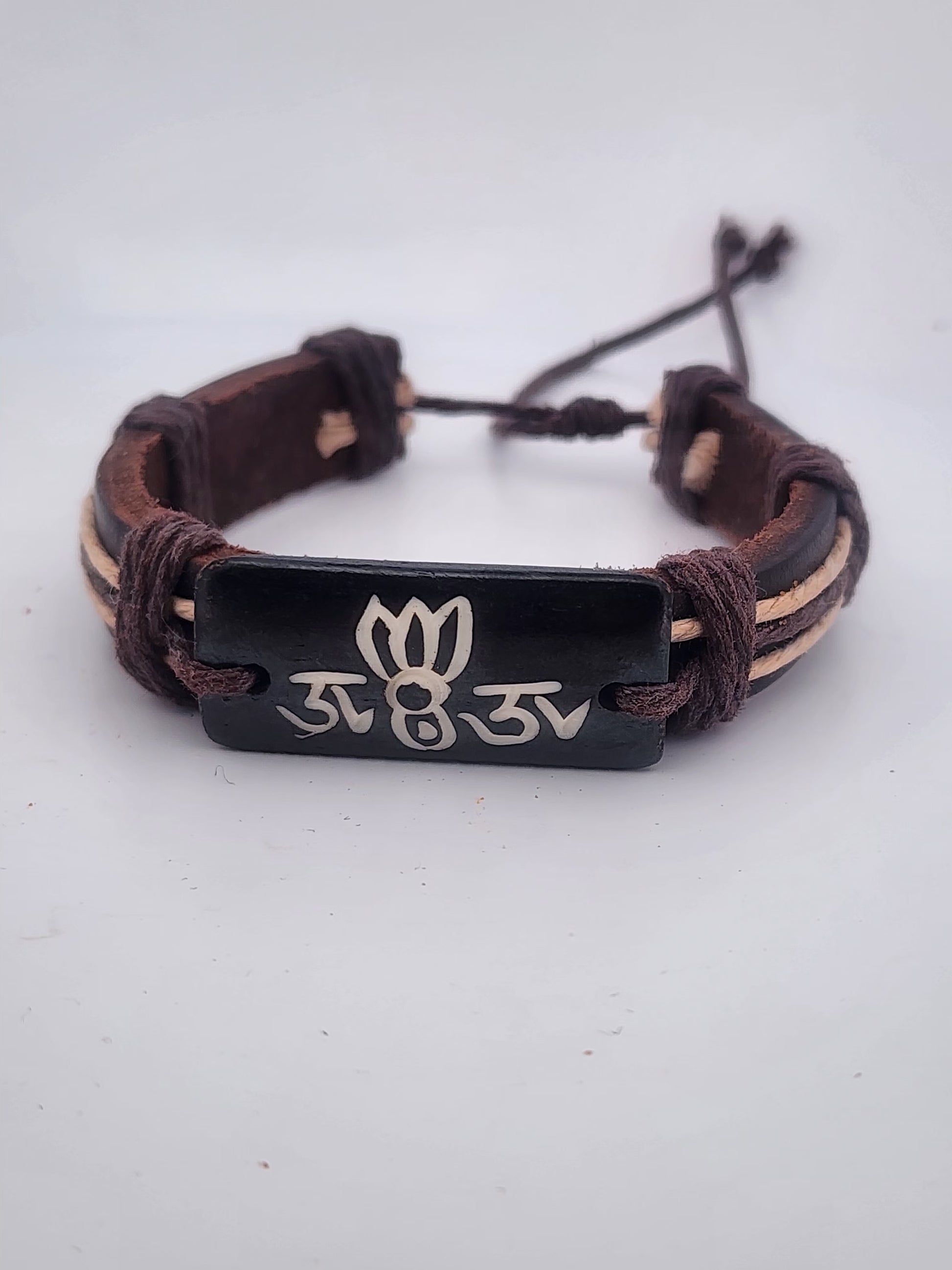 Bracelet with brown leather strap and black metal tag on a white background