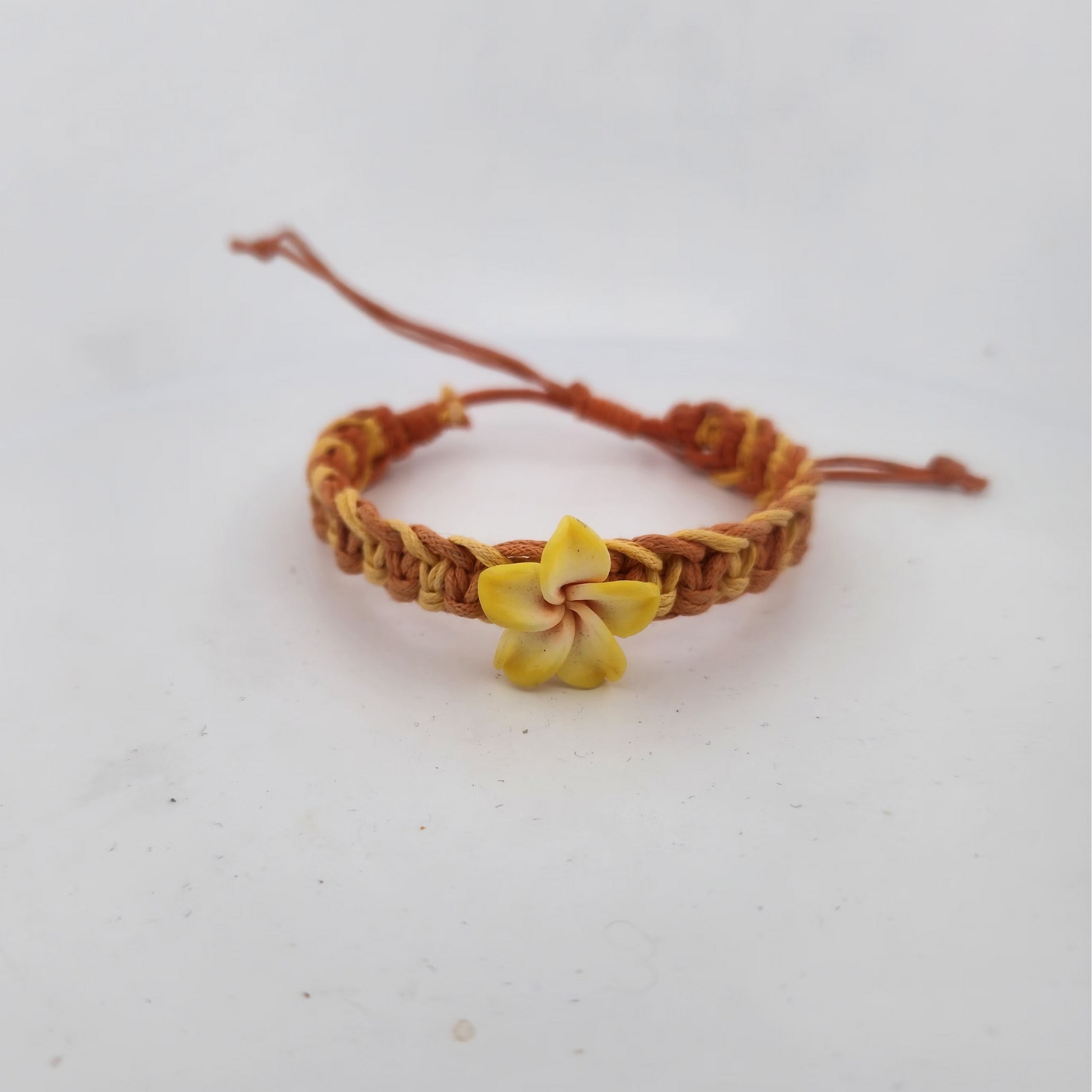Bracelet with a yellow flower charm on a light gray background
