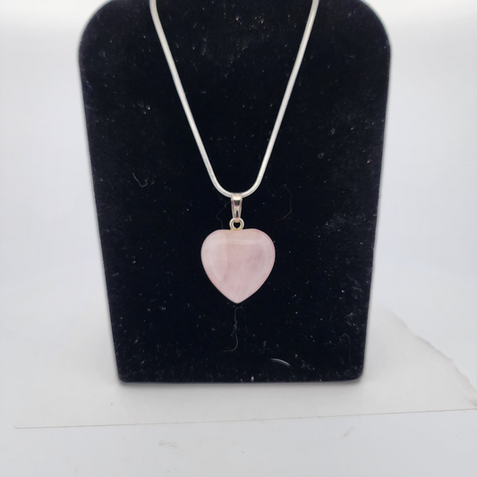 Necklace with a pink heart-shaped pendant on a black velvet stand.