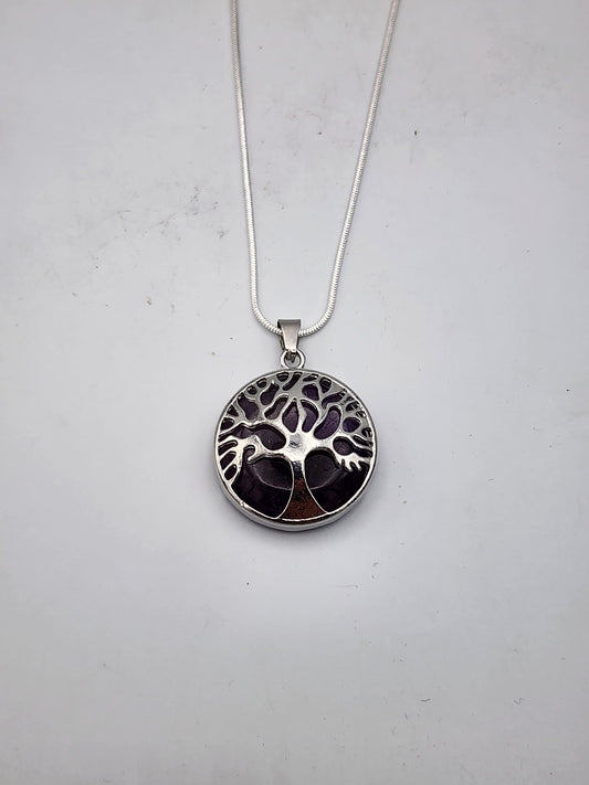 Silver necklace with a tree of life pendant on a light gray background